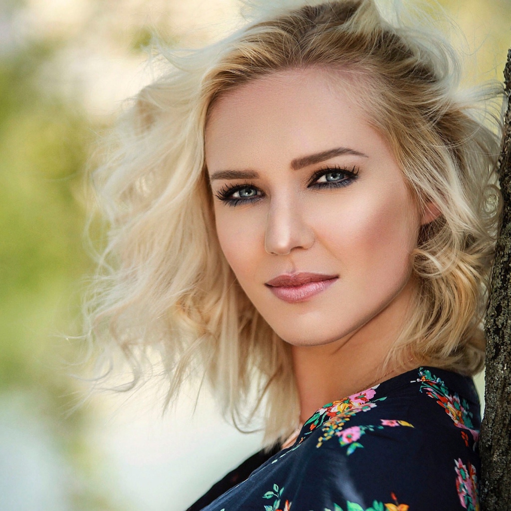 Красивая блондинка с голубыми глазами у дерева 