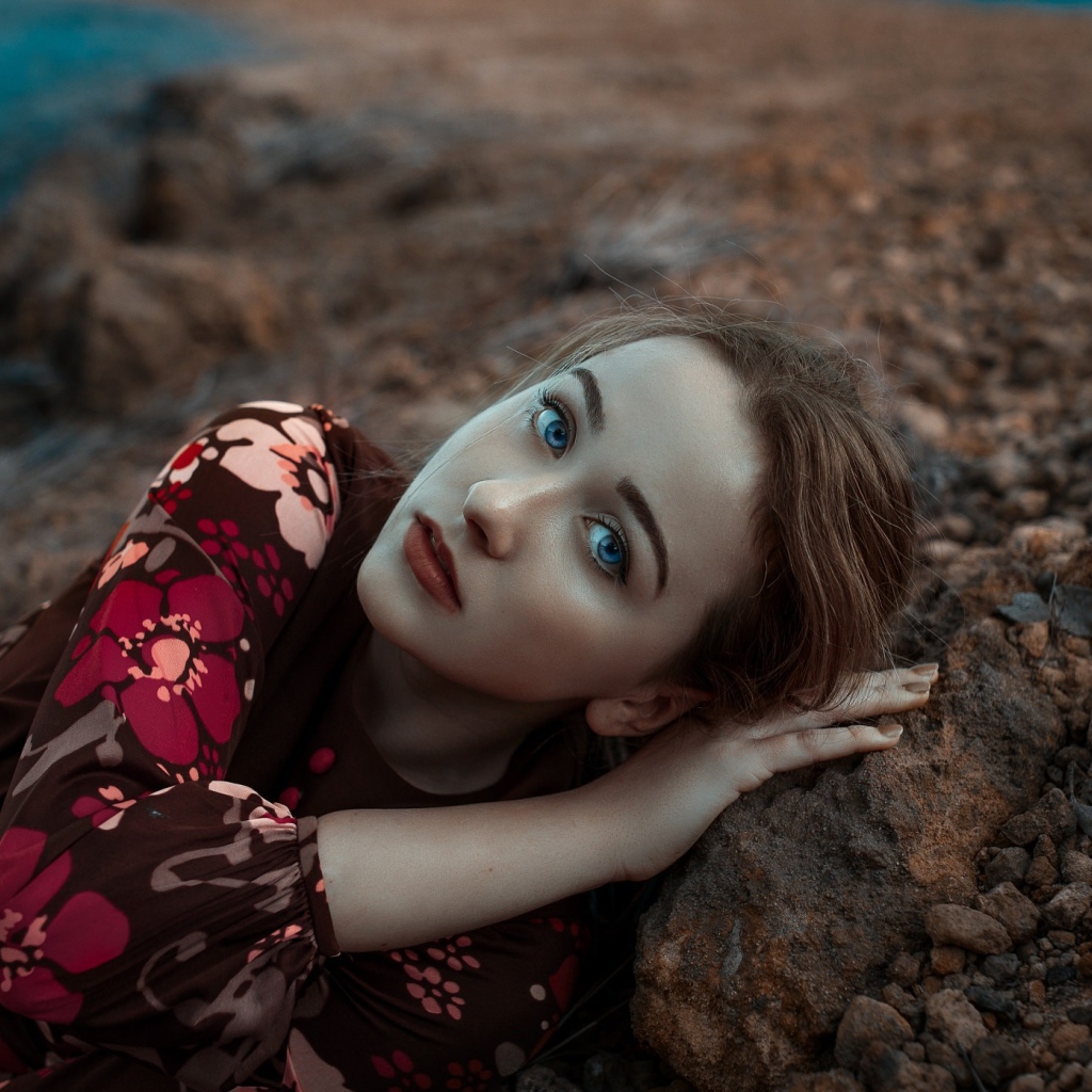 Красивая голубоглазая девушка лежит на камне 