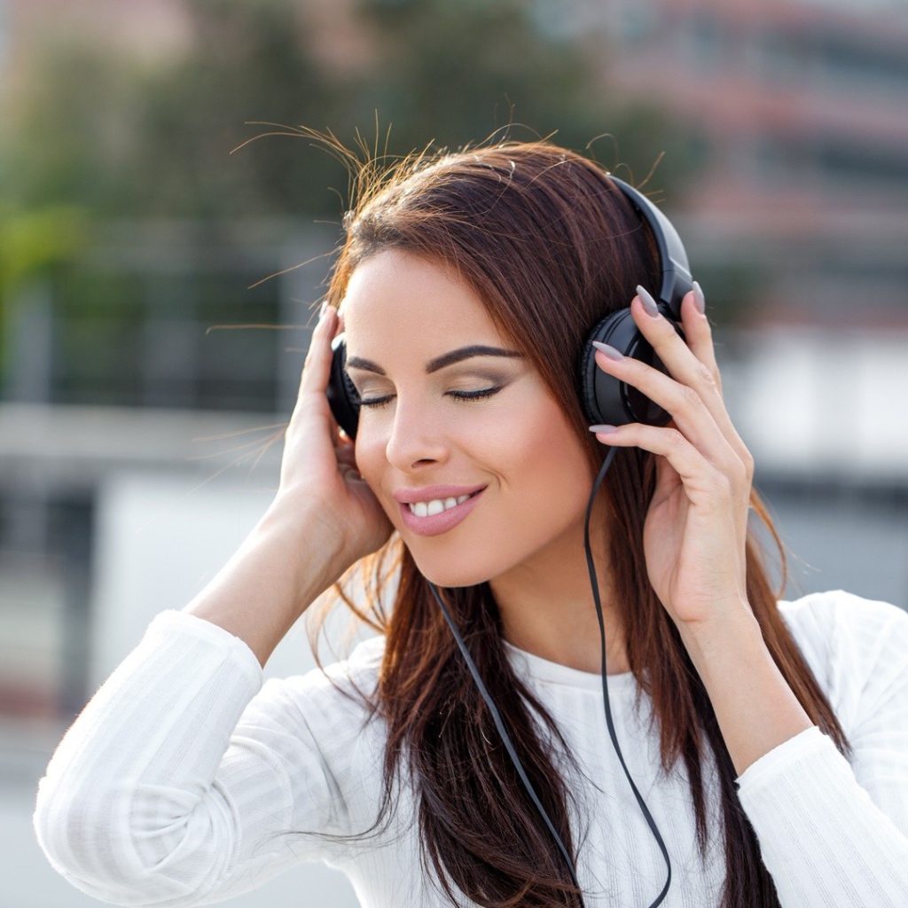 Красивая девушка брюнетка слушает музыку в наушниках 