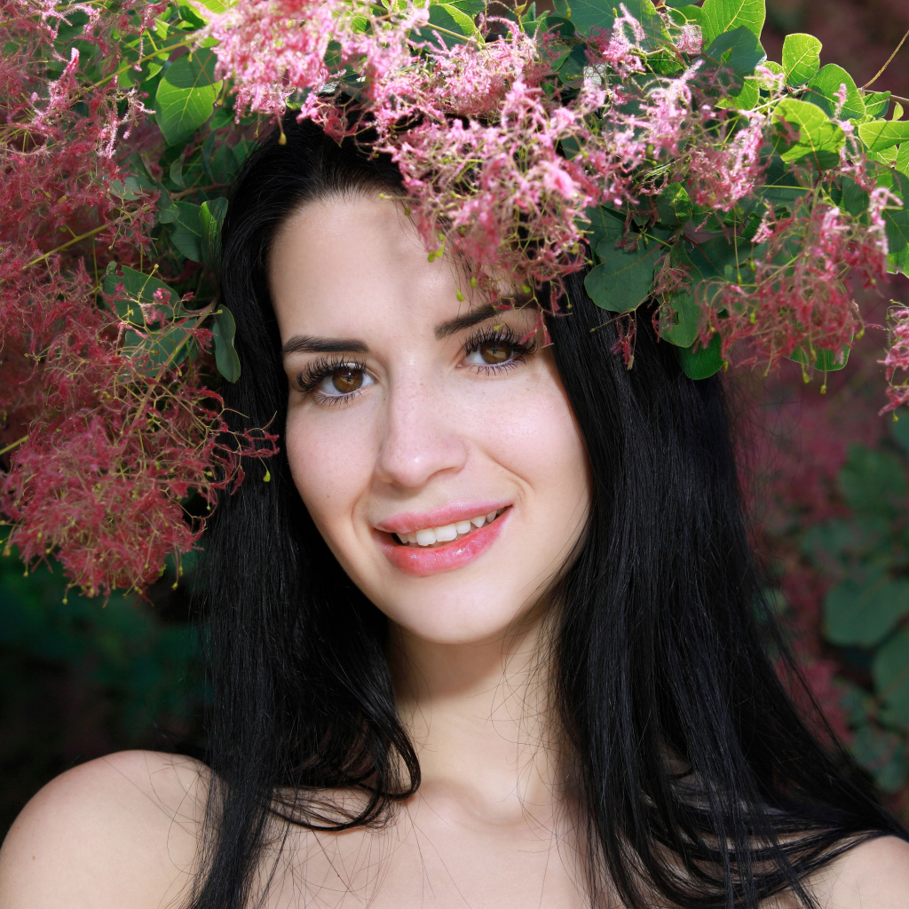 Красивая брюнетка стоит у цветущей ветки