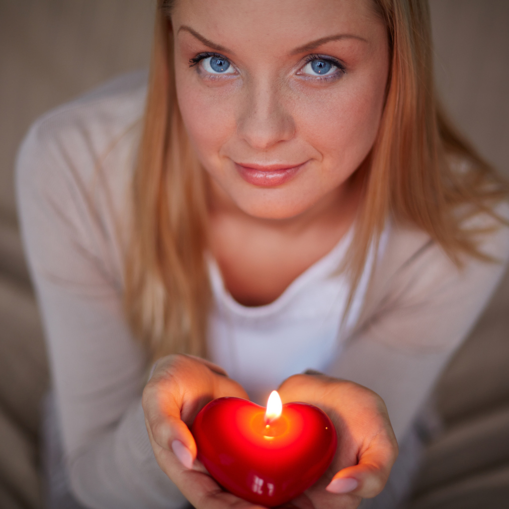 Красивая девушка держит в руках свечу в форме сердца