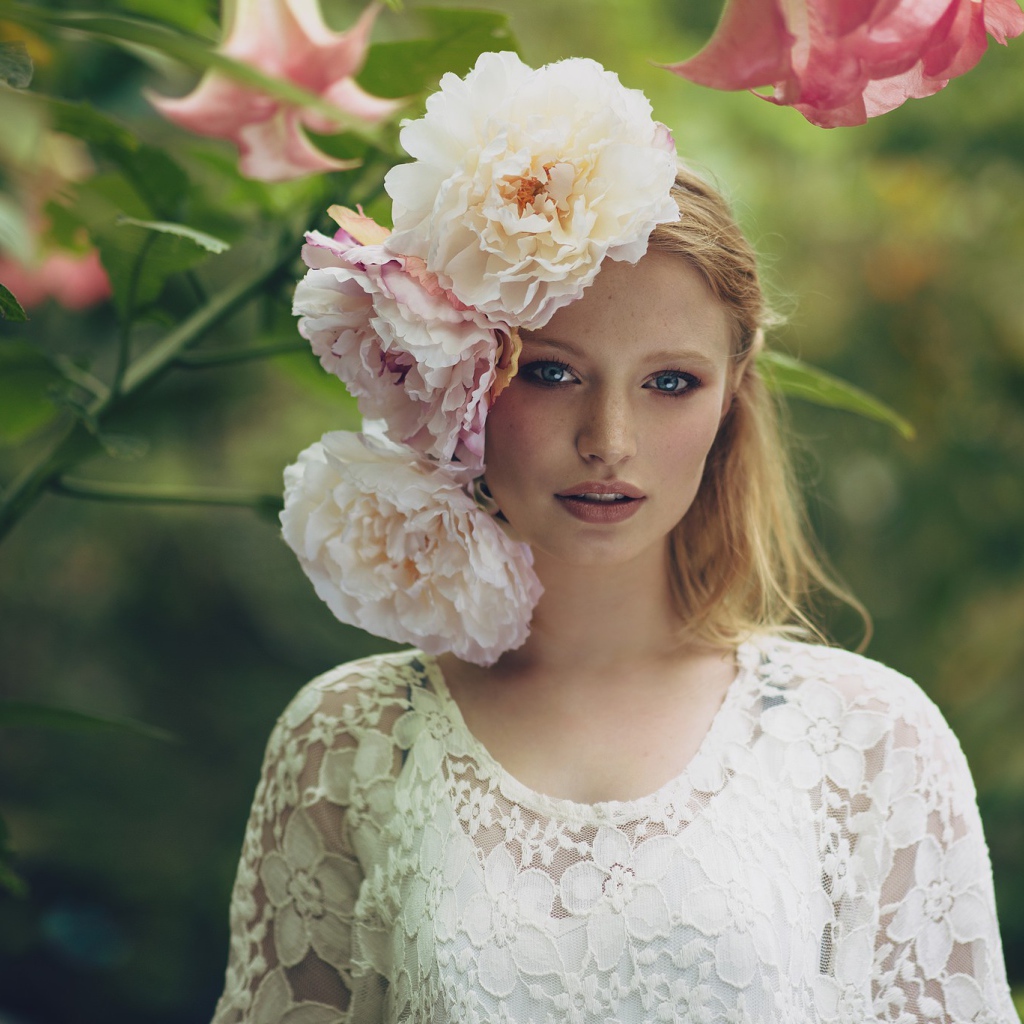 Красивая девушка в белом платье с большими пионами в волосах 