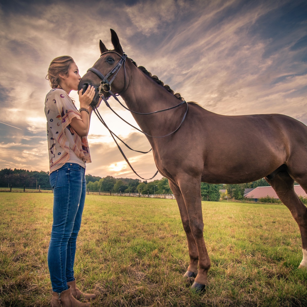 Красивая девушка целует коня под красивым небом