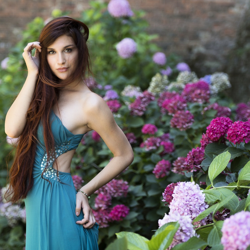 Красивая девушка модель в зеленом платье рядом с цветами гортензии