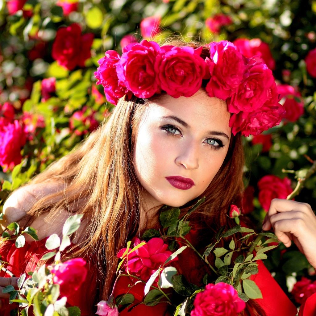 Красивая девушка с венком из красных роз на голове 