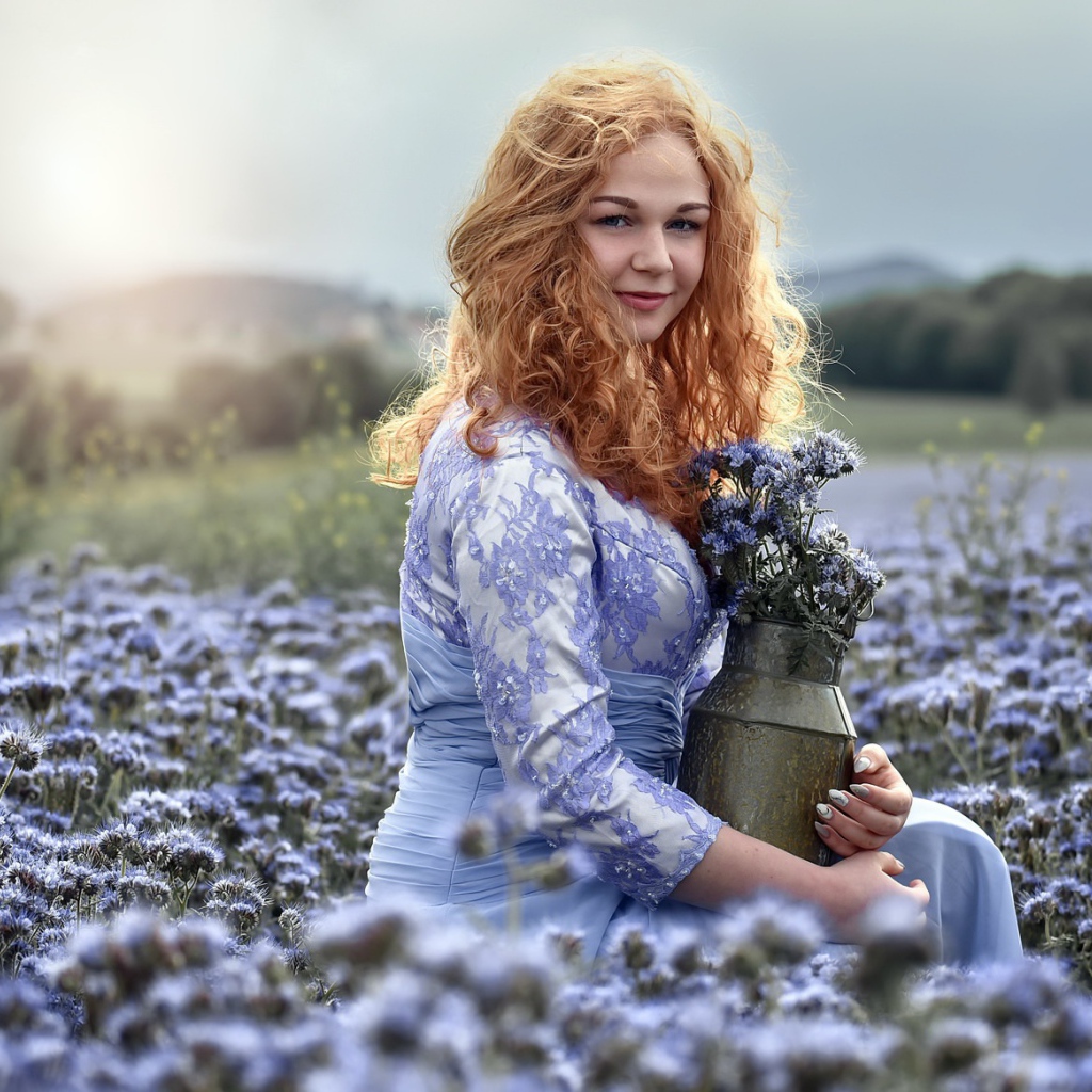 Красивая рыжеволосая девушка собирает цветы