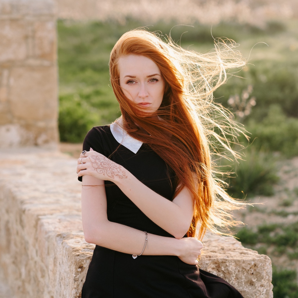 Красивая рыжеволосая девушка в черном платье с рисунком на руке