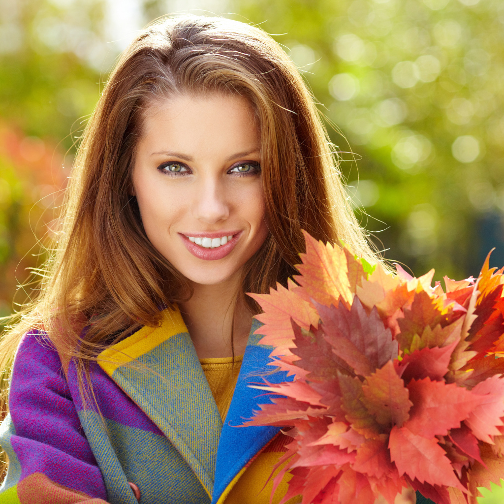 Красивая улыбающаяся девушка с букетом желтых листьев в руке