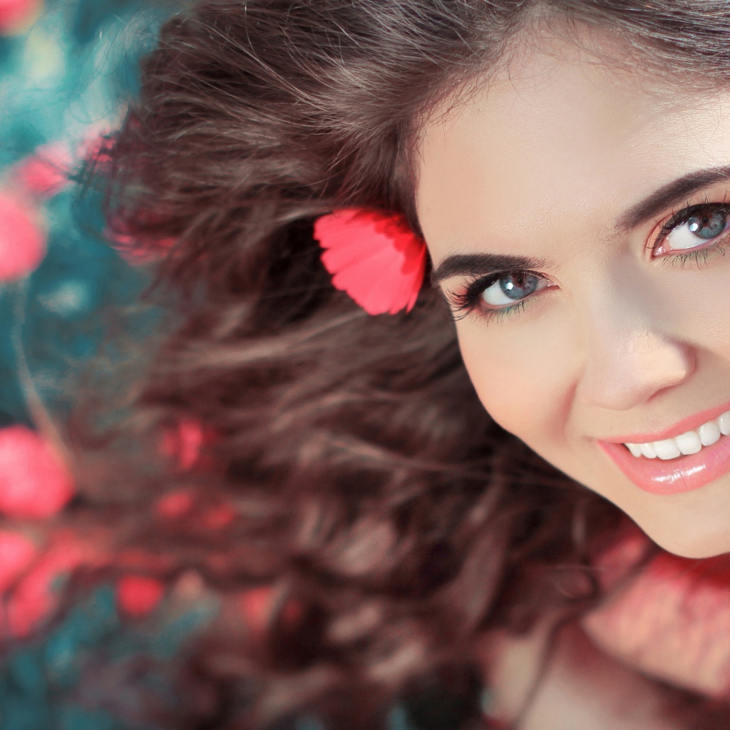 Красивая улыбающаяся девушка с розовыми цветами в волосах 