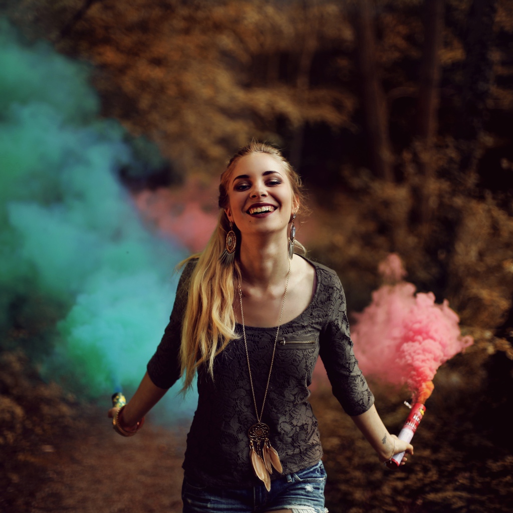Красивая улыбающаяся девушка с дымовыми шашками в руках
