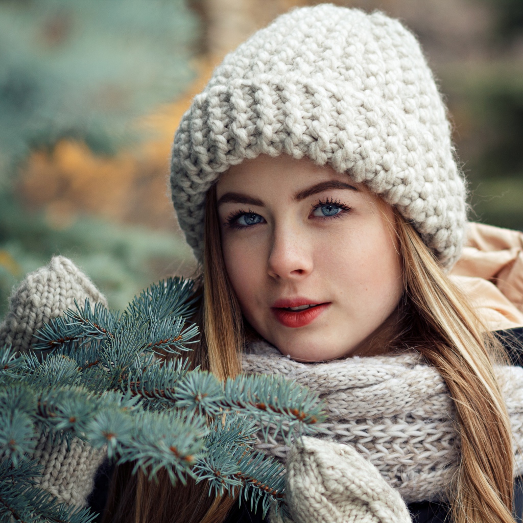 Красивая молодая голубоглазая девушка у еловой ветки зимой