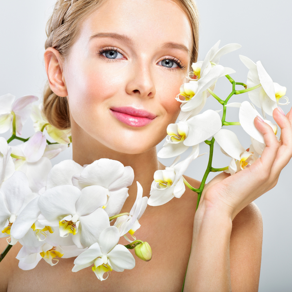 Нежная голубоглазая девушка с цветами орхидеи в руках