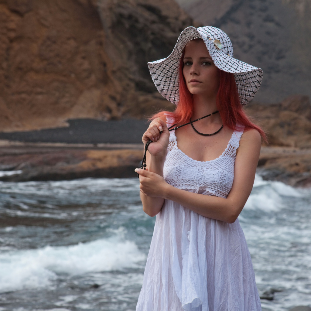 Рыжеволосая девушка в шляпе и белом платье у реки