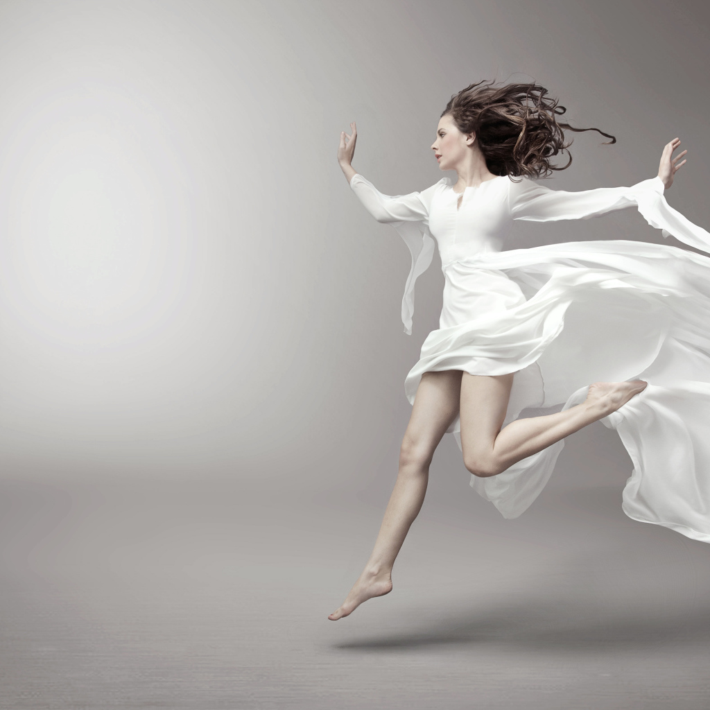 Бегущая красивая девушка в белом платье на сером фоне