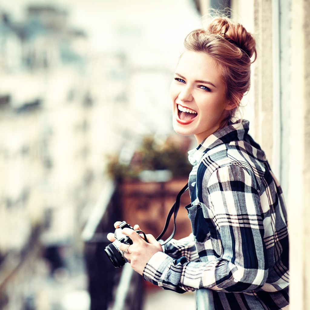 Улыбающаяся девушка в клетчатой рубашке с фотоаппаратом 