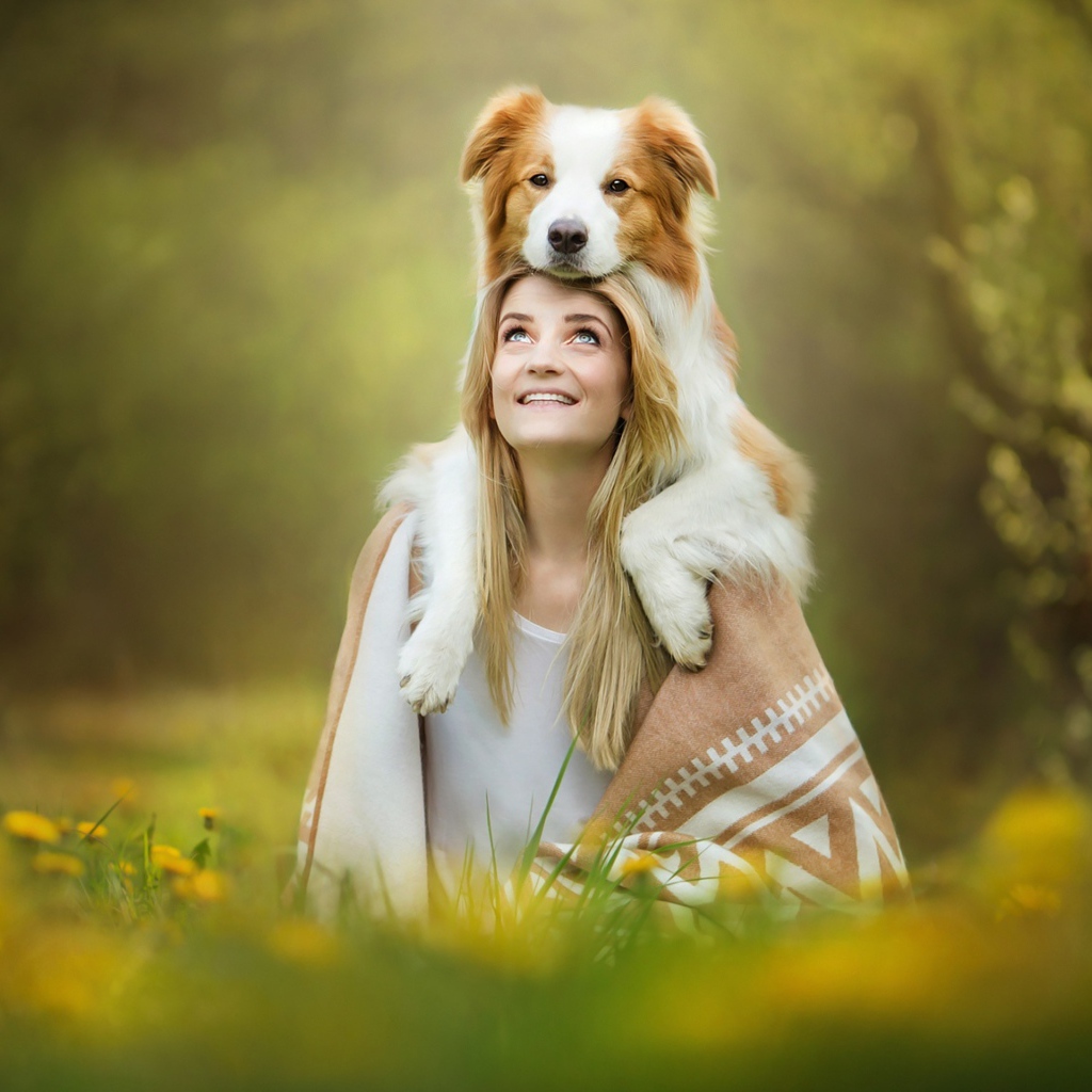 Улыбающаяся девушка с собакой сидят на траве