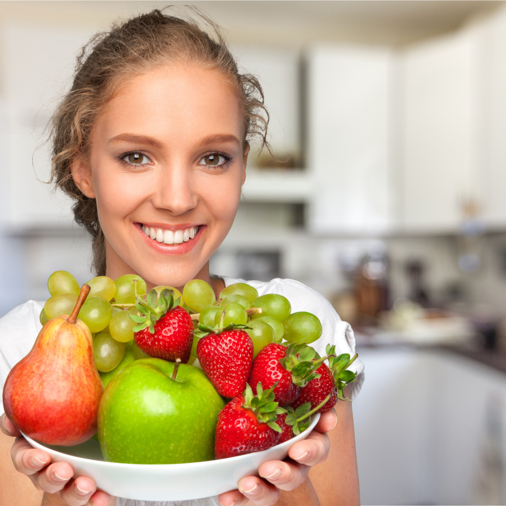 Улыбающаяся девушка со свежими фруктами 