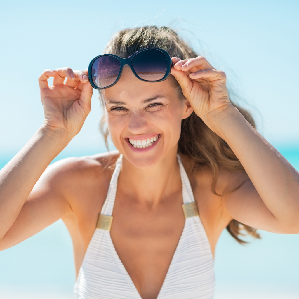 Улыбающаяся девушка с очками на голове