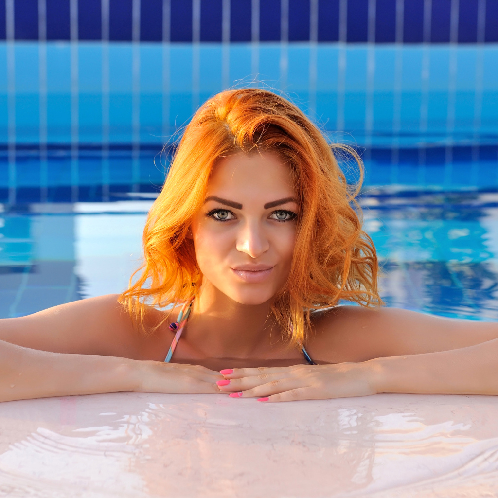 Эффектная рыжеволосая девушка в бассейне
