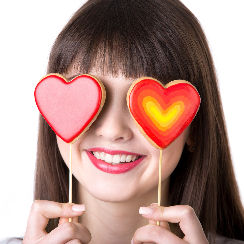 Красивая девушка шатенка закрыла глаза леденцами в форме сердца