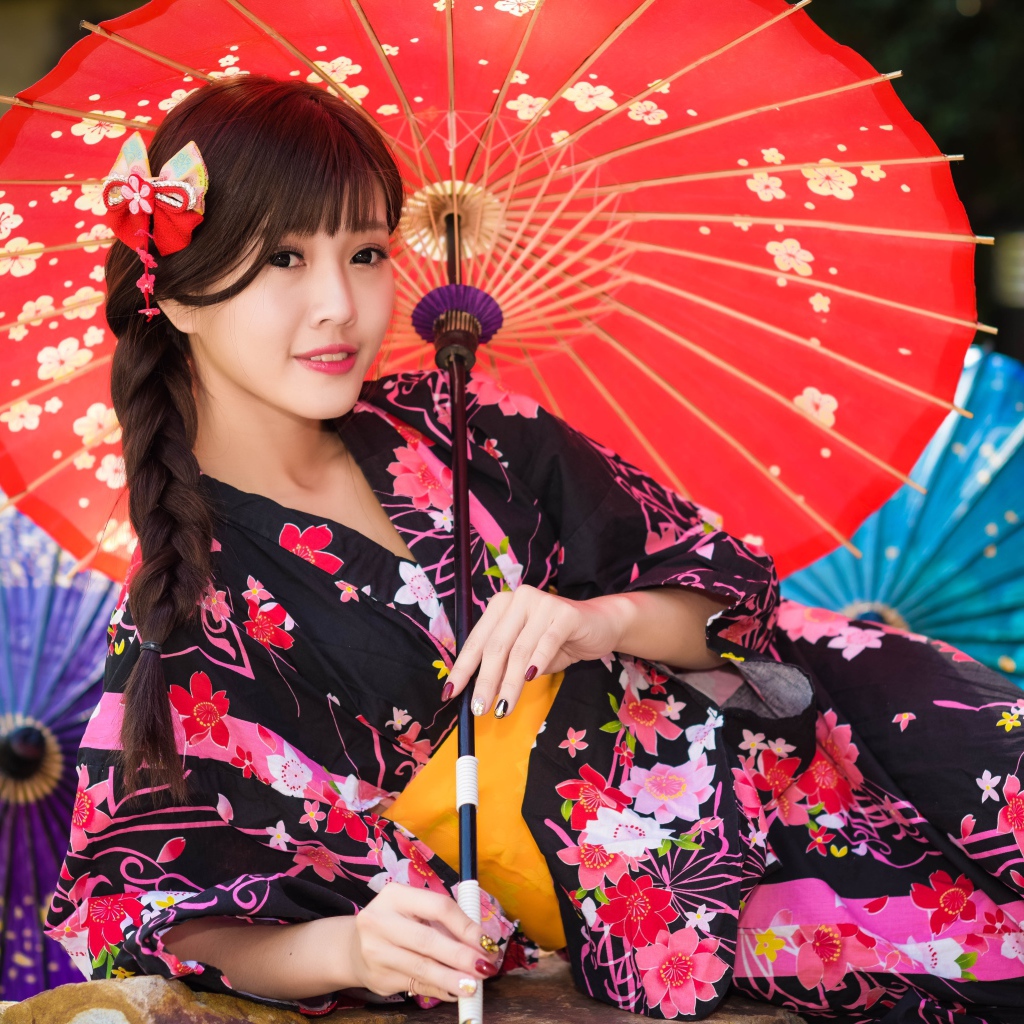 Молодая азиатка в кимоно с разноцветными зонтиками