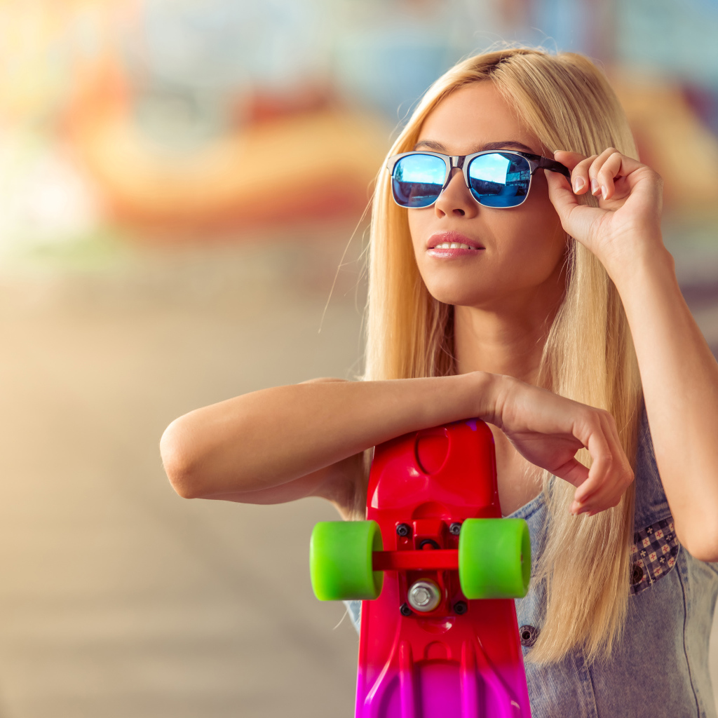 Молодая блондинка в солнечный очках со скейтбордом