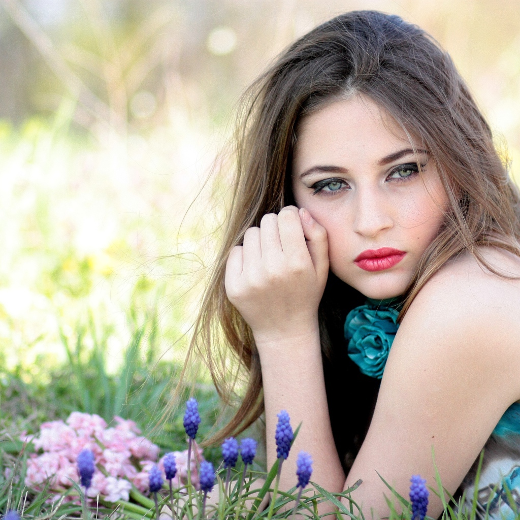 Молодая девушка брюнетка с голубыми глазами лежит на траве 