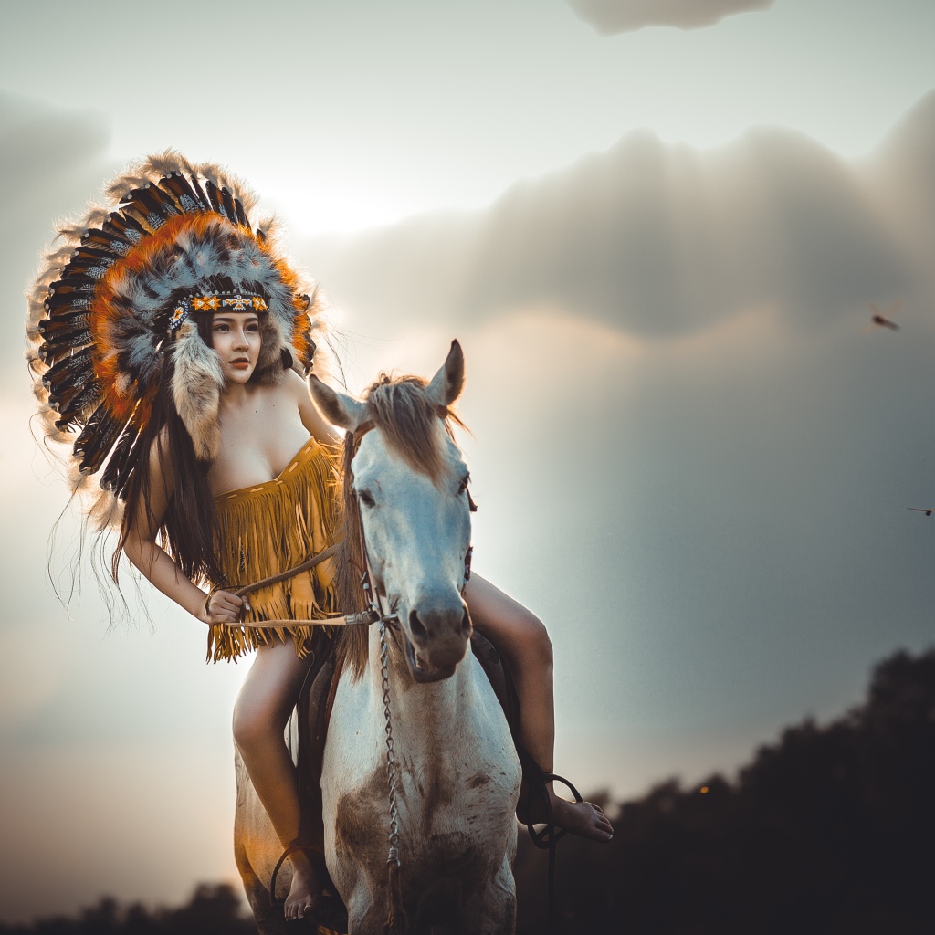 Молодая девушка в костюме индейца на коне