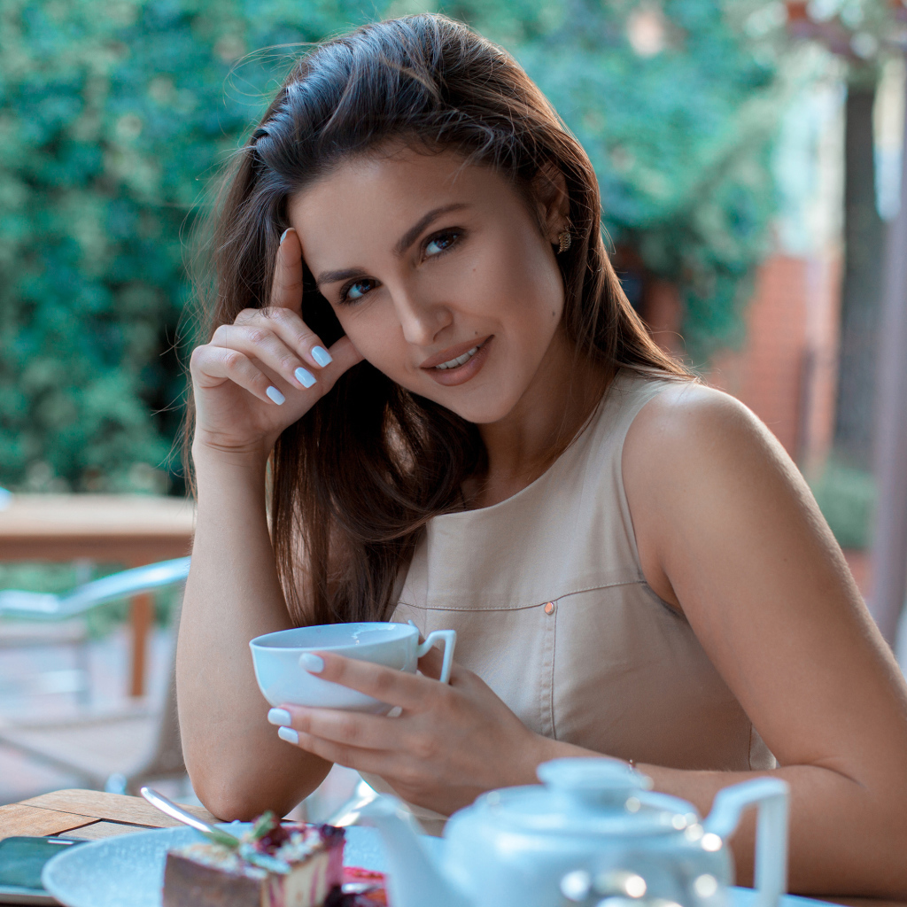 Молодая улыбающаяся девушка с чашкой кофе в кафе