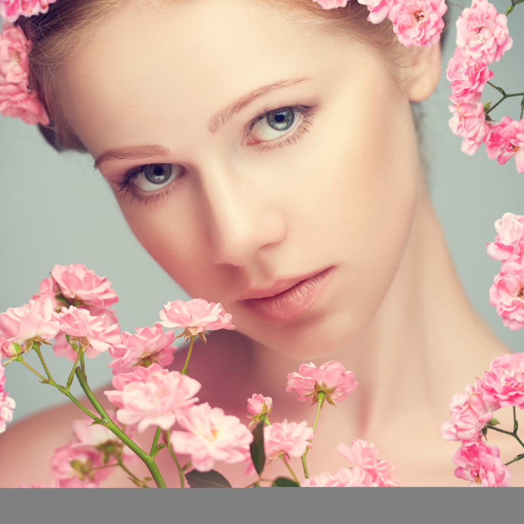 Молодая нежная девушка с розовыми розами на сером фоне