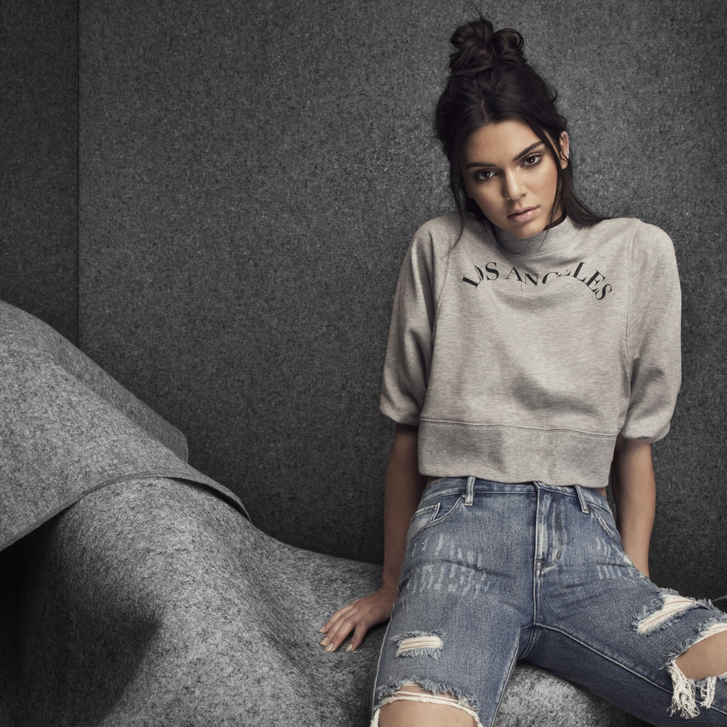 Модель Кендалл Дженнер в рваных джинсах на сером фоне