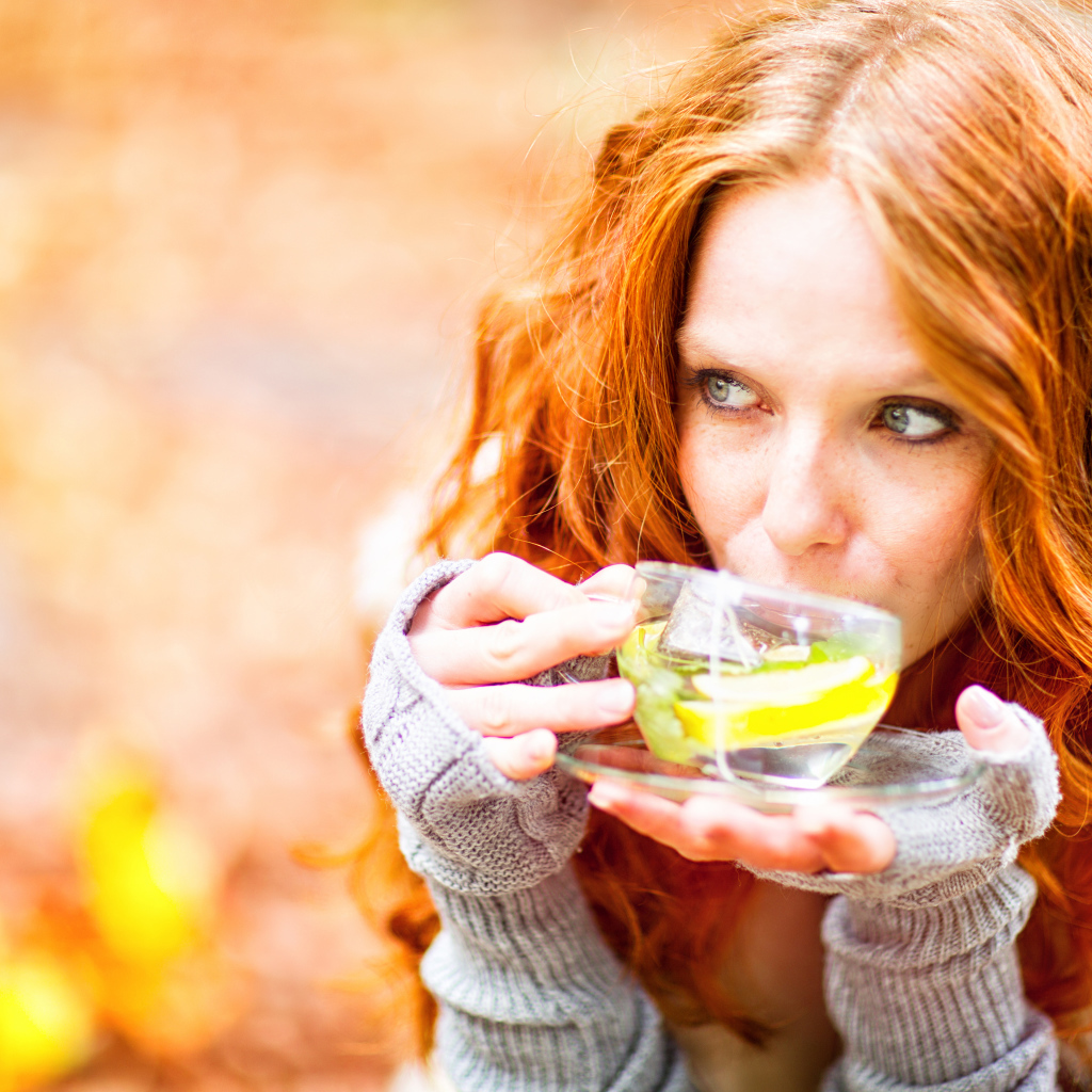 Рыжеволосая девушка модель с чашкой зеленого чая 