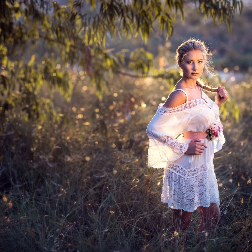 Молодая девушка модель в красивом белом платье с косой на голове