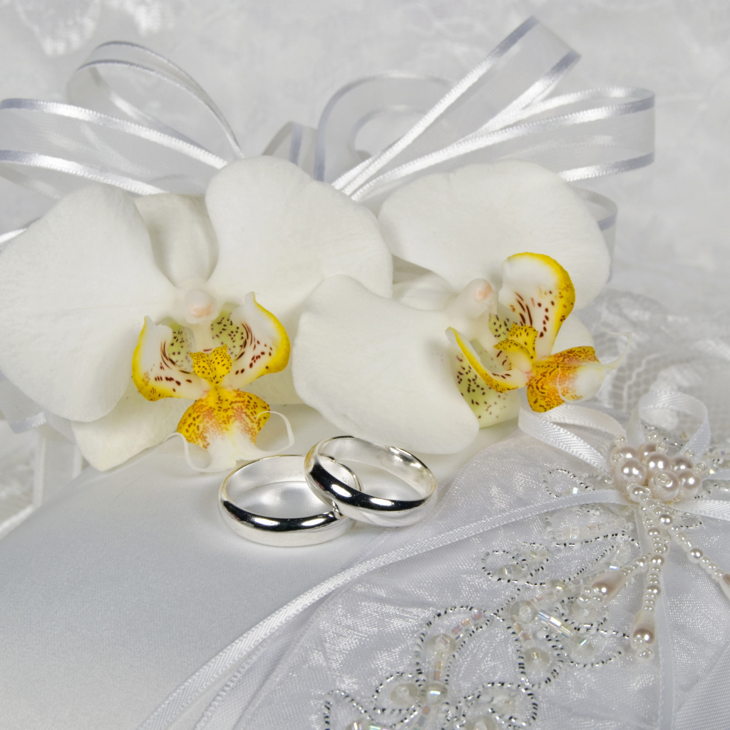 Два обручальных кольца с нежными белыми цветами орхидеи