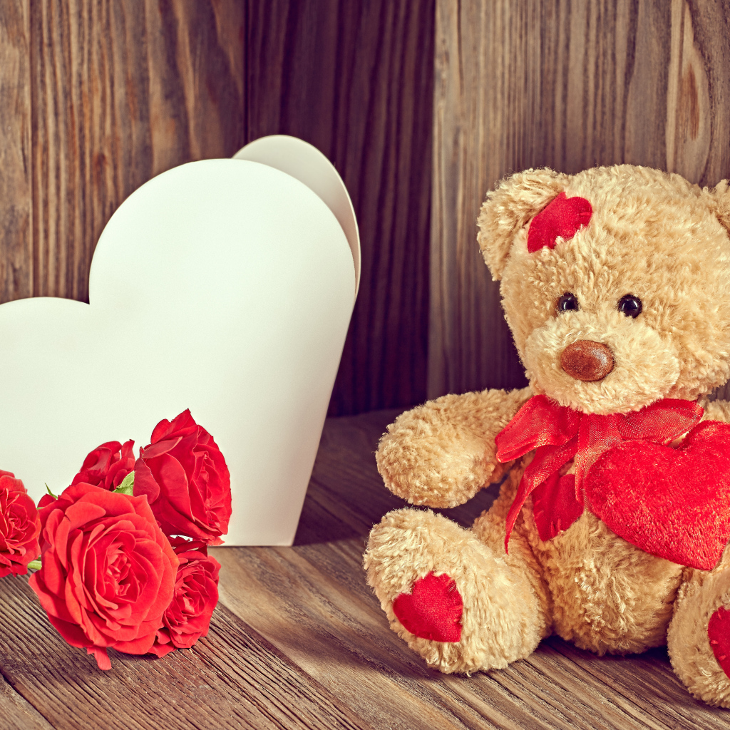 Плюшевый медведь с большим белым бумажным сердцем и красными розами