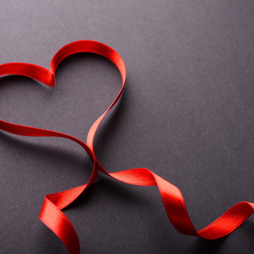 Красное сердце из атласной ленты на сером фоне