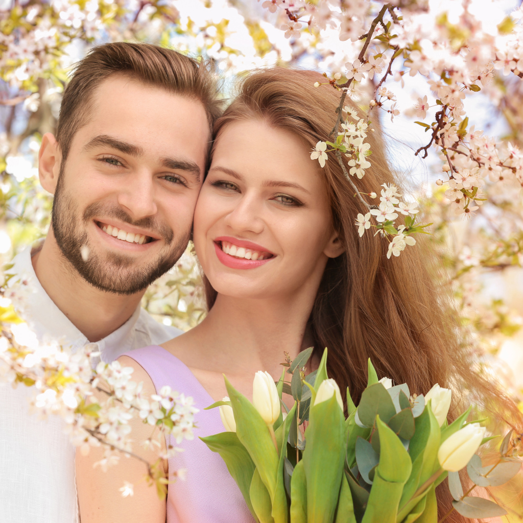 Улыбающаяся влюбленная пара у цветущего дерева