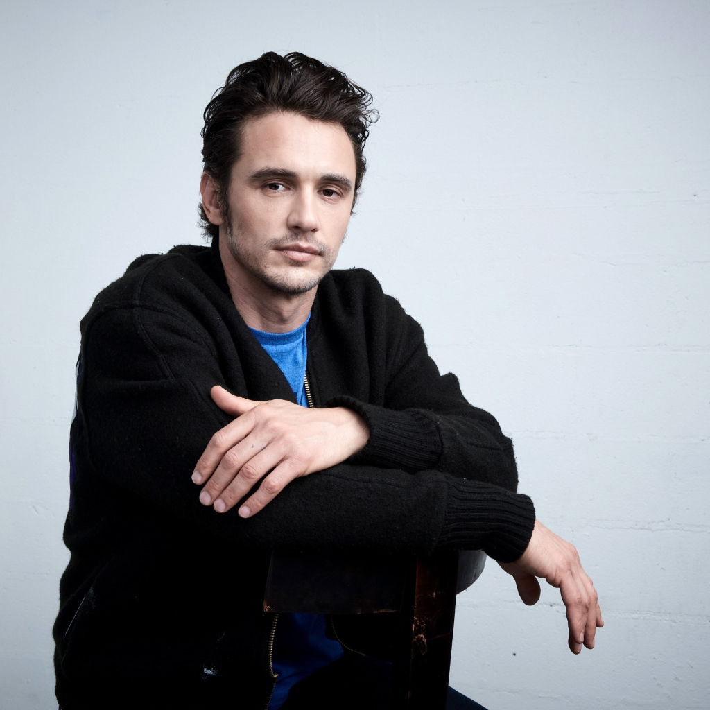 Актер Джеймс Франко в черной кофте на сером фоне