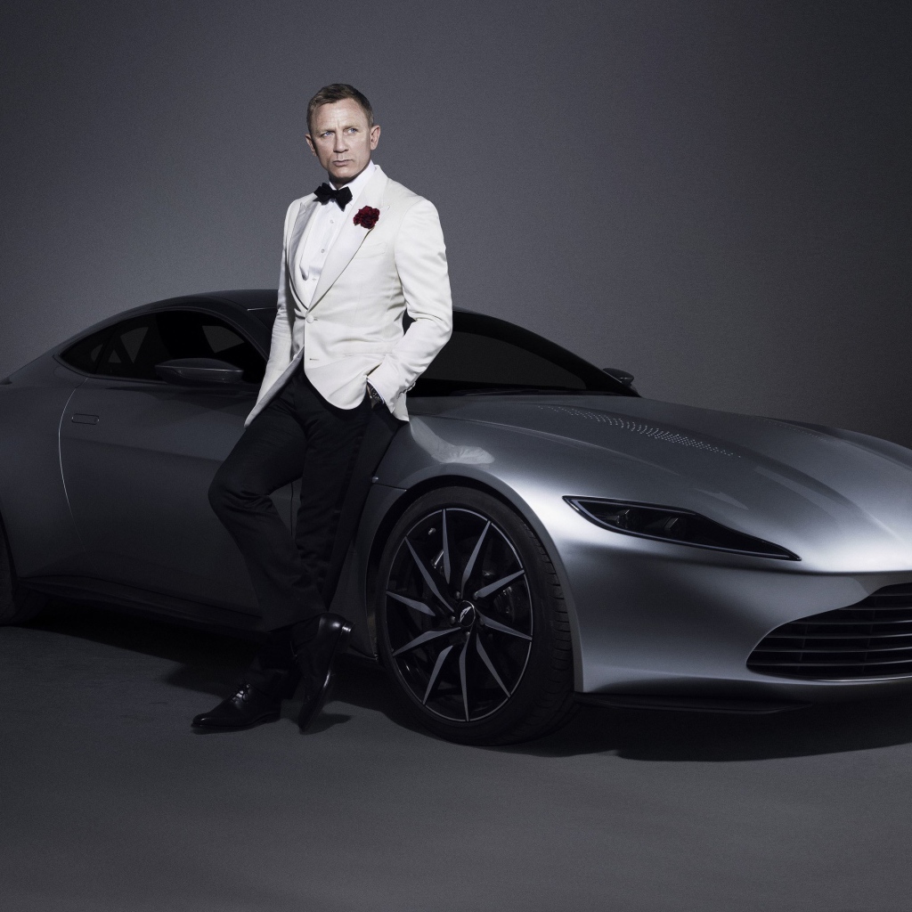 Знаменитый актер Дэниел Крэйг рядом с серебристым автомобилем Aston Martin