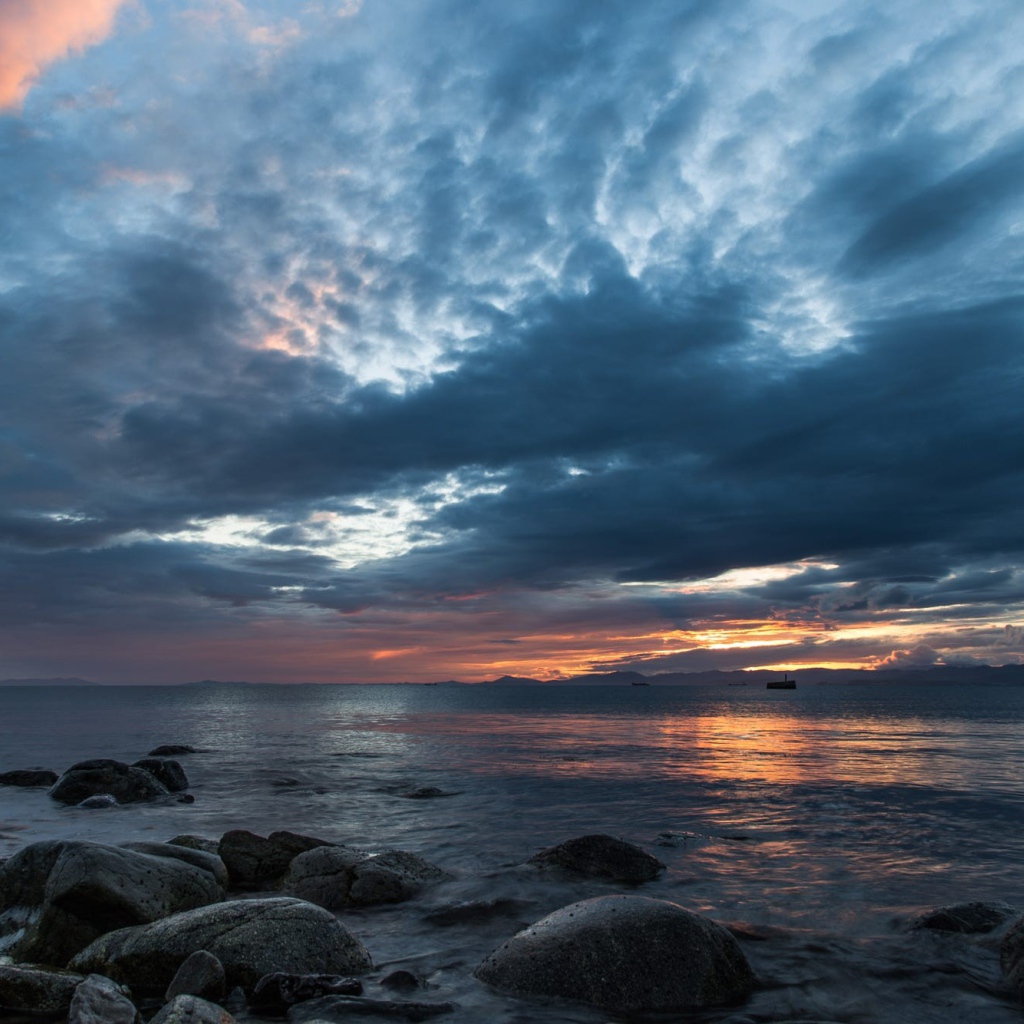 Валуны в воде на берегу на фоне пасмурного неба 
