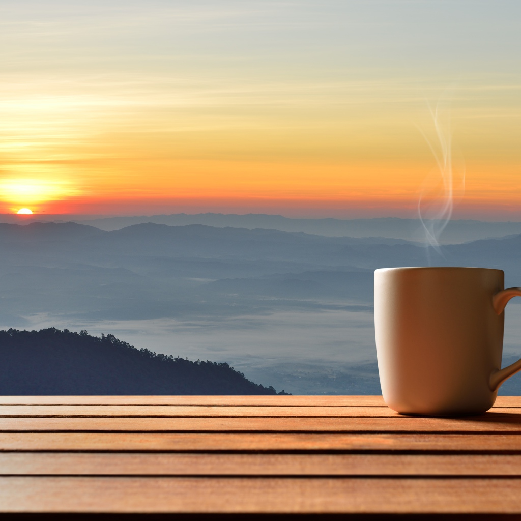 Чашка фоне на фоне горизонта с восходящим солнцем