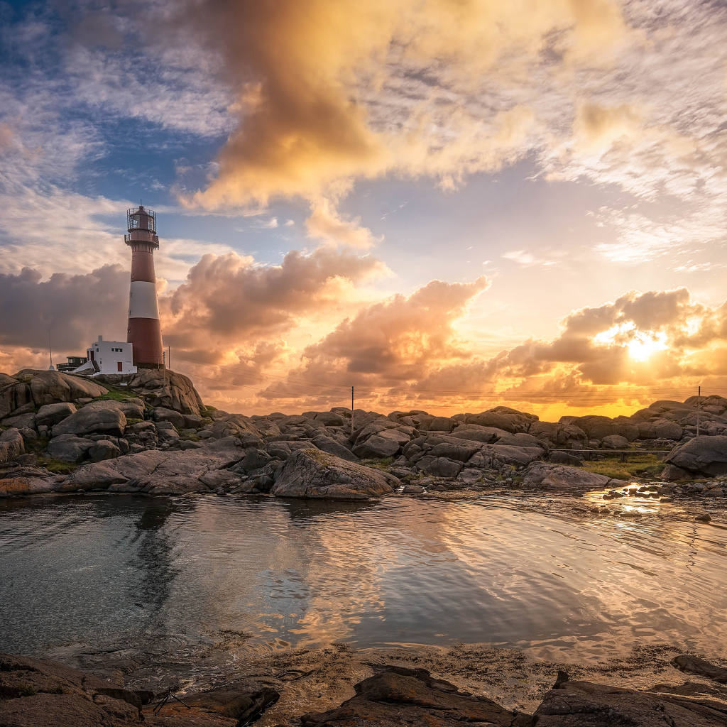 Маяк на каменном побережье на фоне красивого неба