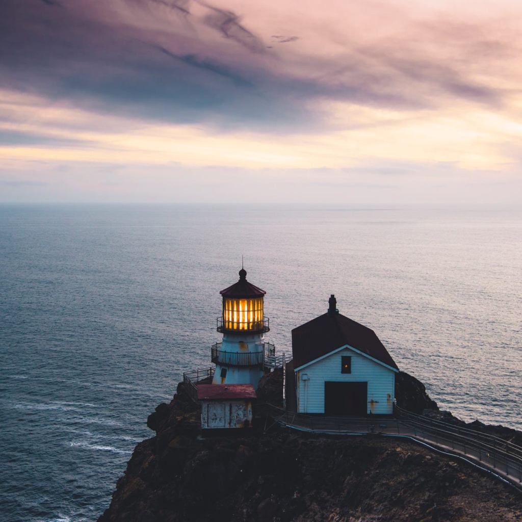 Маяк на скале на фоне горизонта океана 