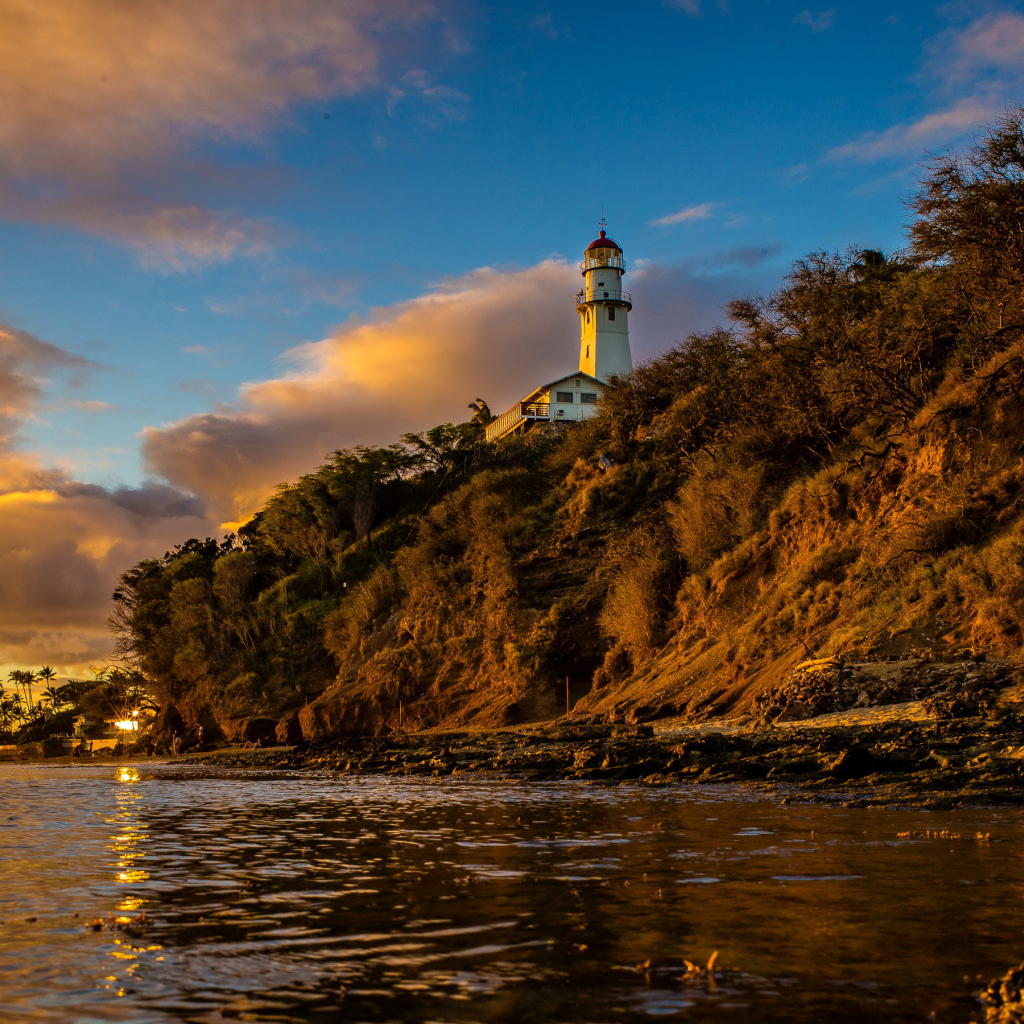 Маяк на склоне скалы на закате 