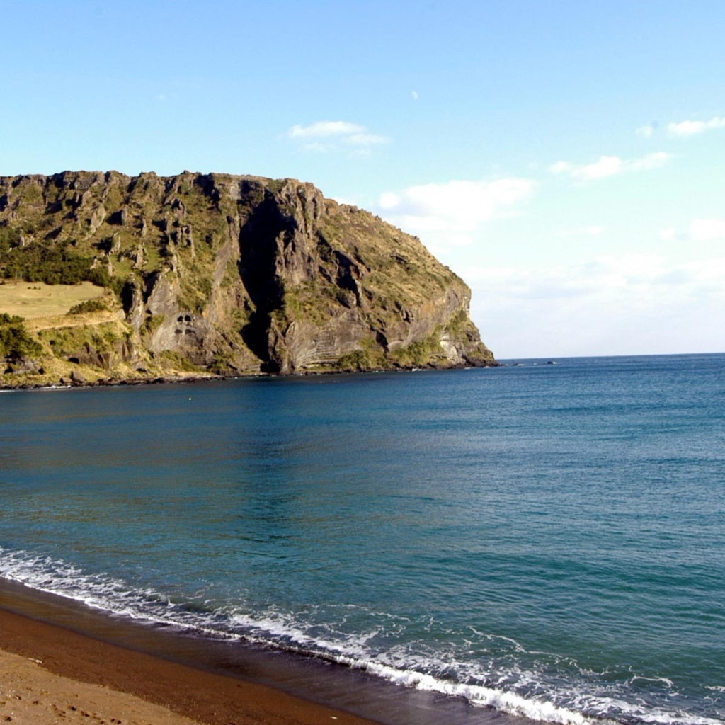 Гора на фоне спокойной воды моря под голубым небом