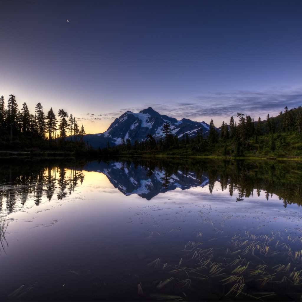 Заснеженная гора и лес отражается в озере вечером