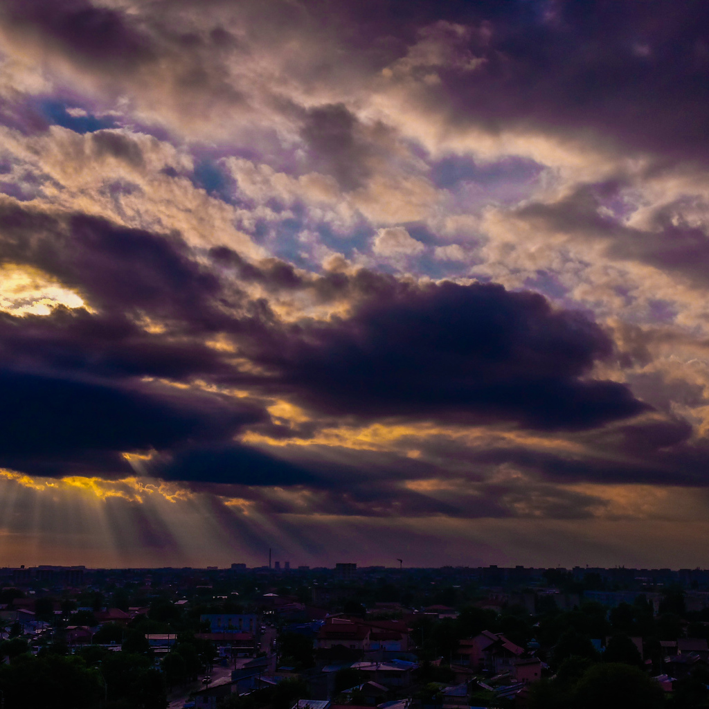 Лучи солнца пробиваются сквозь облака над городом