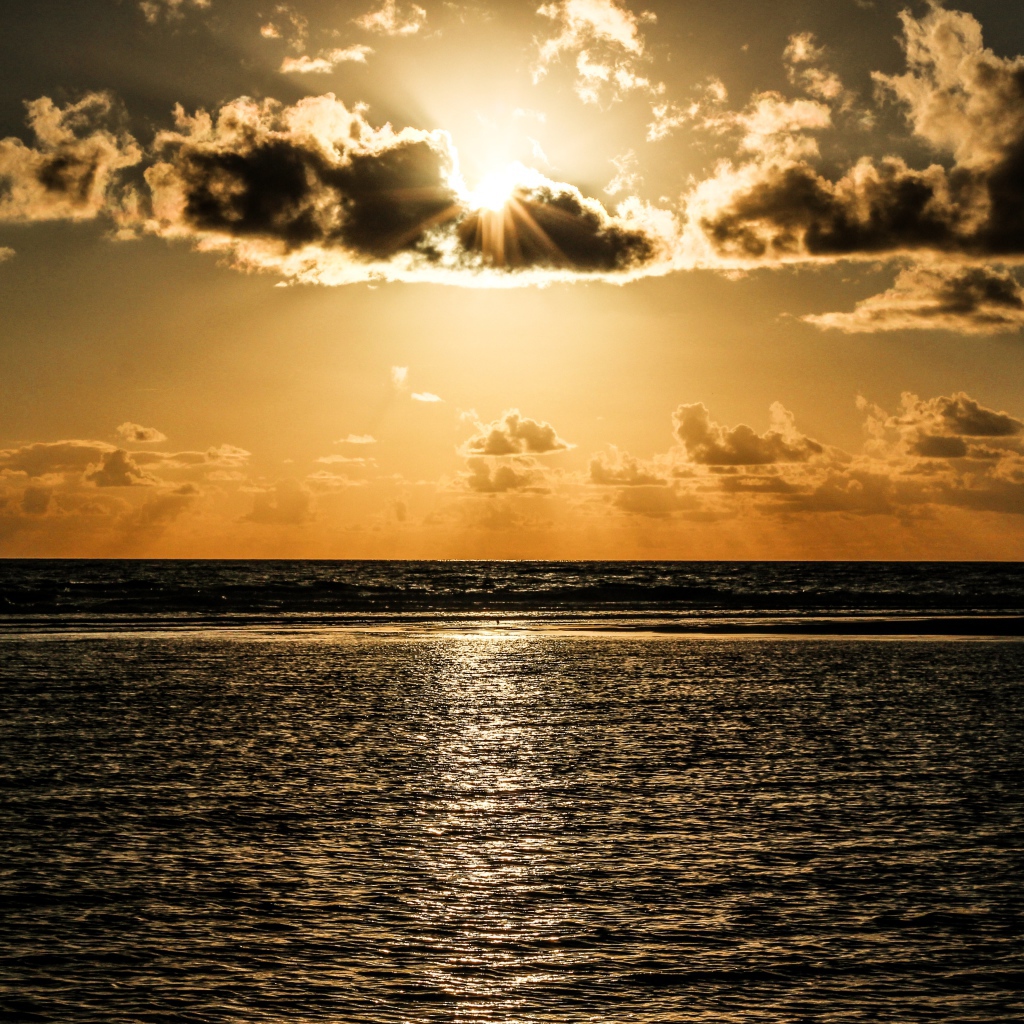 Солнечные лучи пробиваются сквозь облака над океаном