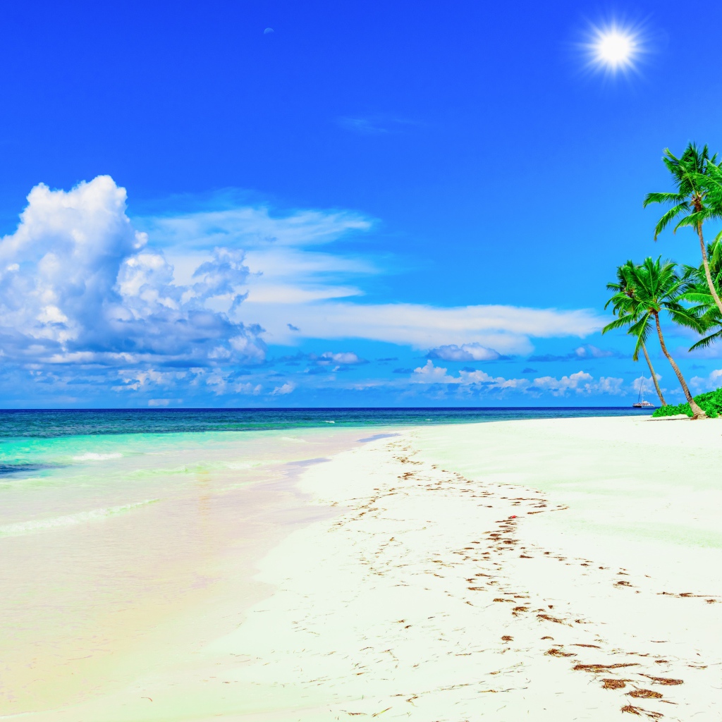 Следы на белом песке на тропическом пляже под красивым голубым небом