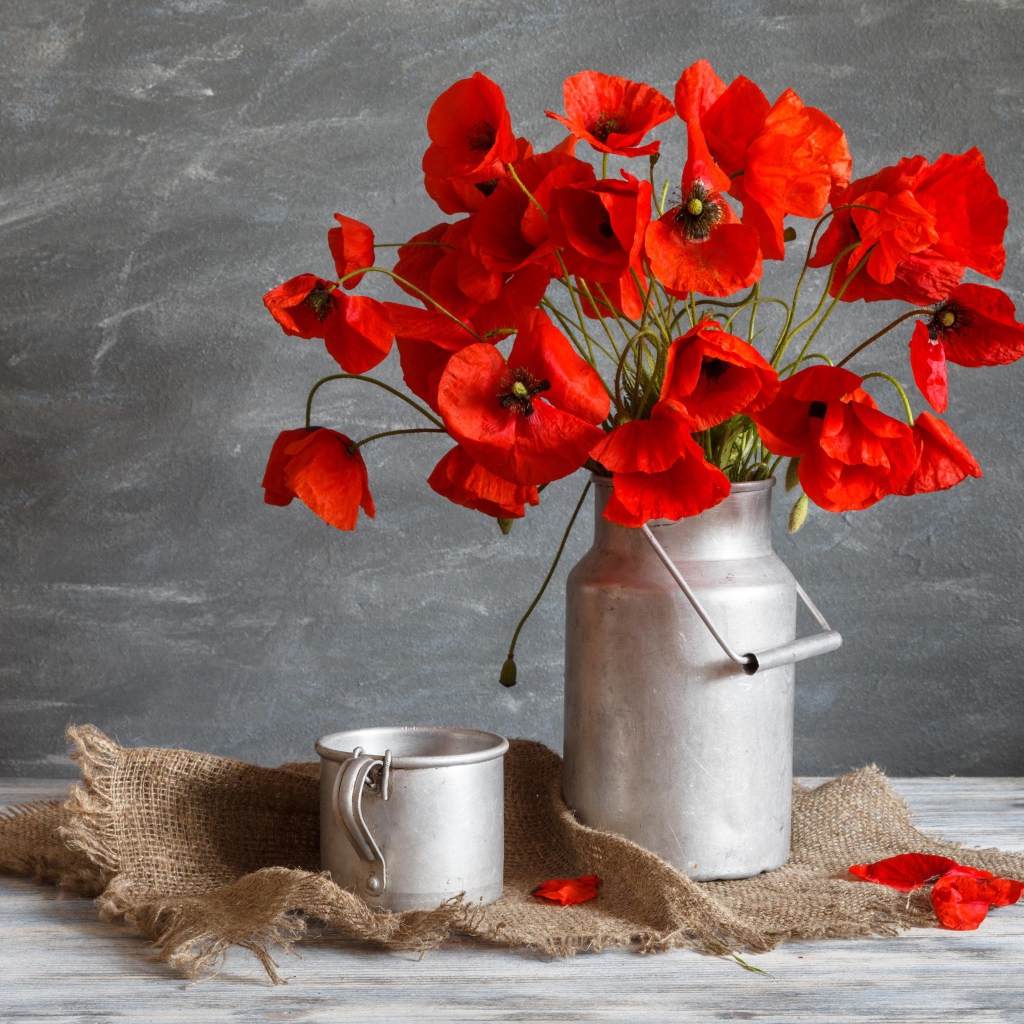 Букет красных маков в железном бидоне на столе с кружкой